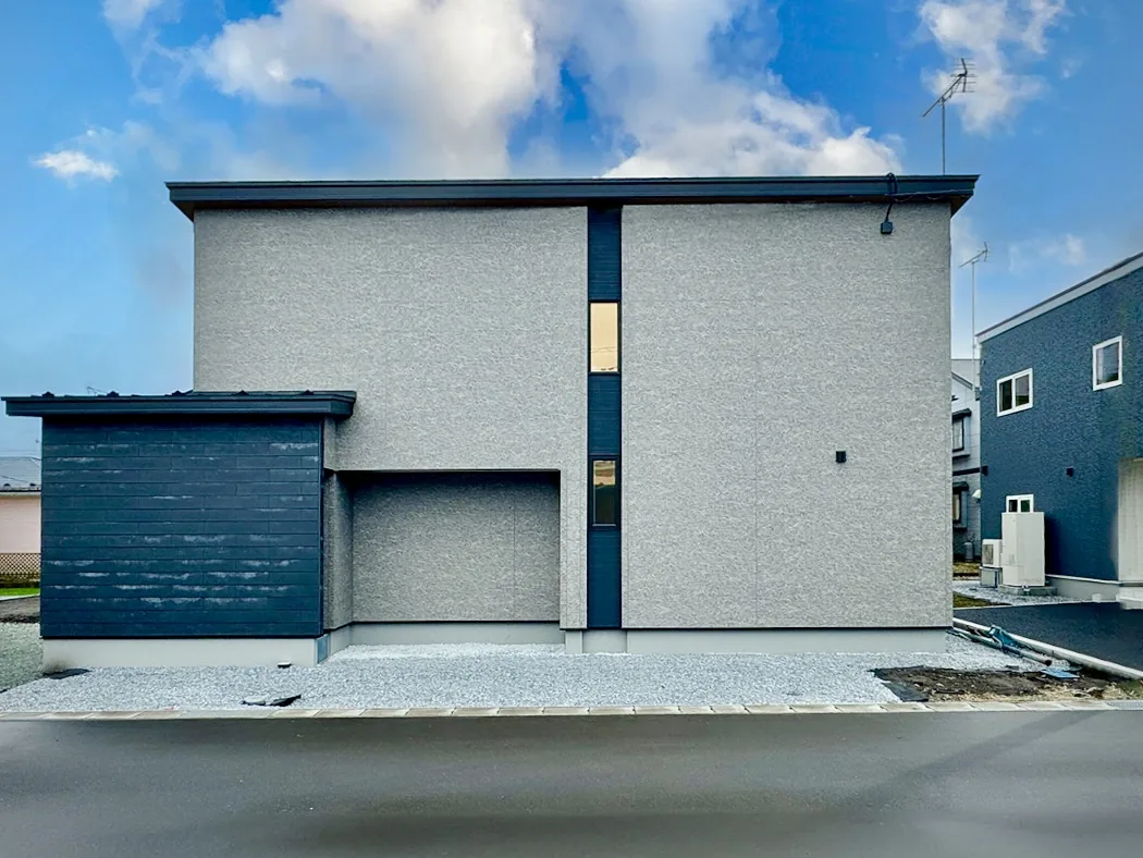 グレーの外壁にネイビーのアクセントの二階建て|暮らしに上質さを添える家